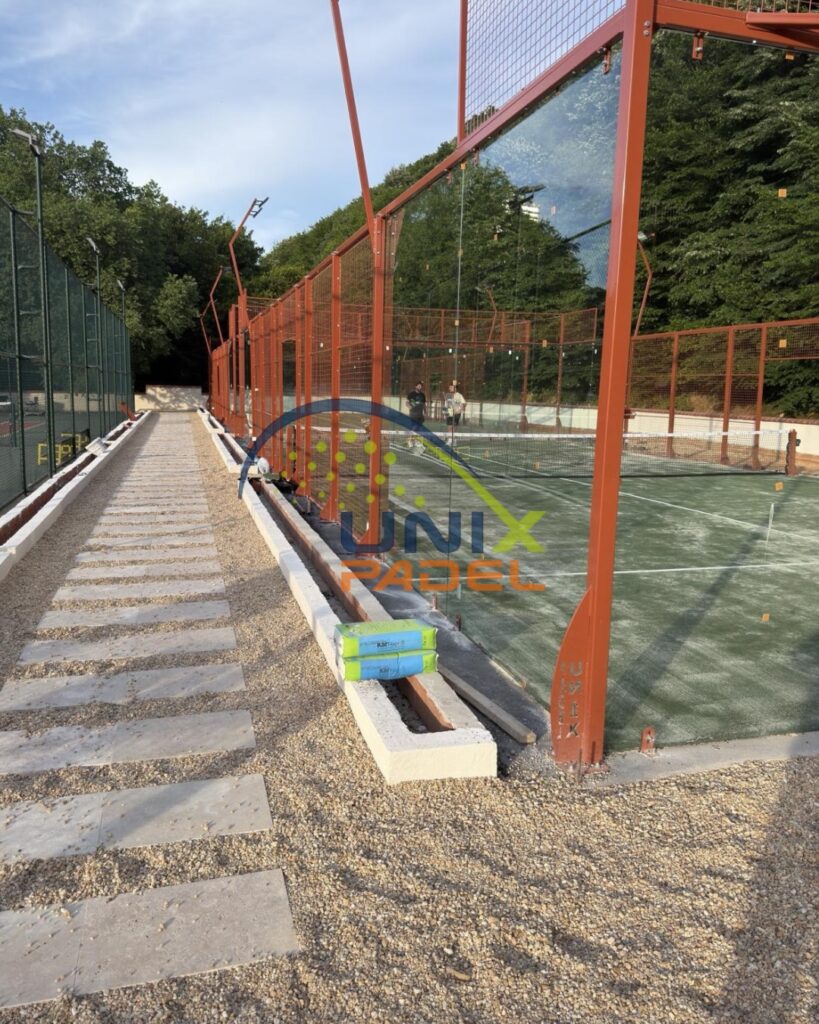 Outdoor professional padel court featuring custom colored steel structure and glass panels installed by Unixpadel